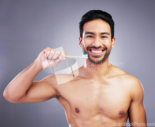 Image of Dental, portrait and a man brushing teeth on a studio background for cleaning, grooming and hygiene. Happy, wellness and an Asian person with a toothbrush for care of mouth isolated on a backdrop