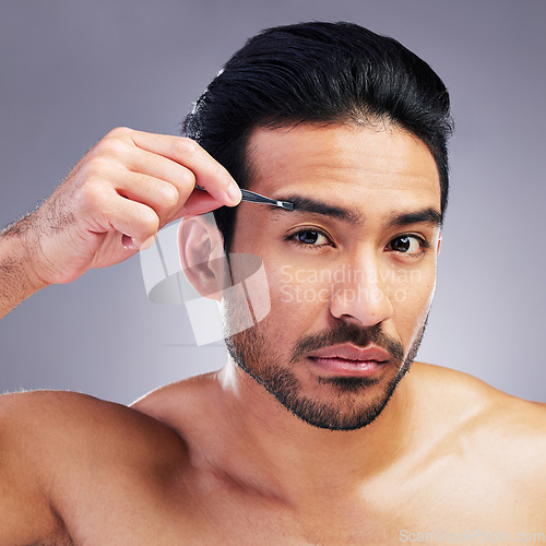 Image of Tweezer, eyebrow and portrait of a man in studio for beauty, hygiene or grooming. Facial hair removal, epilation and face of asian person for skincare, self care and cosmetic tools on grey background