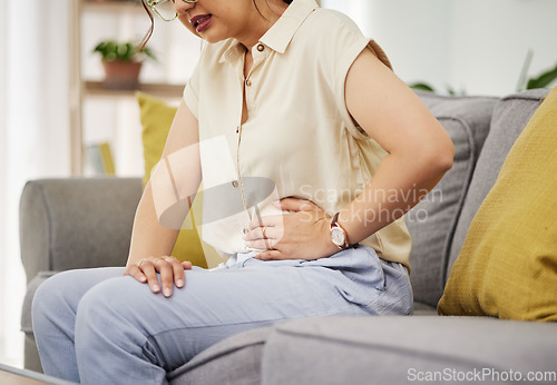 Image of Sick woman, sofa and stomach pain for health, digestion and nausea of pms at home. Closeup of female person, menstruation and abdomen bloating of constipation, period and endometriosis in living room