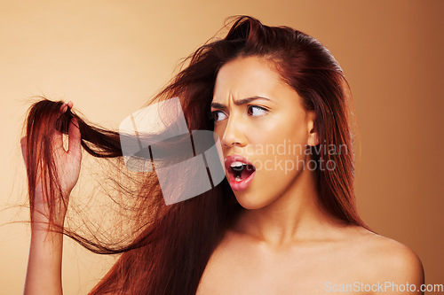 Image of Damaged, hair and a woman upset in studio about salon, split end and hairdresser treatment. Stress, disaster and shocked model person with dry texture or hairstyle crisis on a brown background