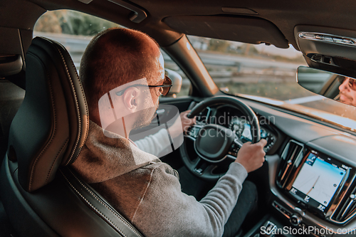 Image of A man with a sunglasses driving a car at sunset. The concept of car travel