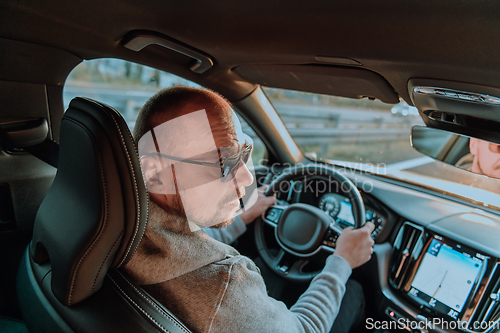 Image of A man with a sunglasses driving a car at sunset. The concept of car travel