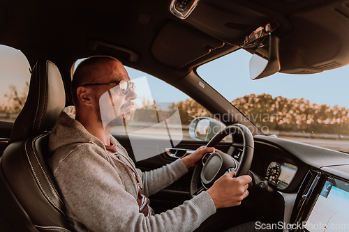 Image of A man with a sunglasses driving a car at sunset. The concept of car travel