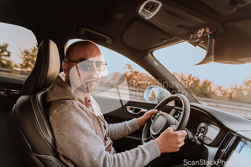 Image of A man with a sunglasses driving a car at sunset. The concept of car travel