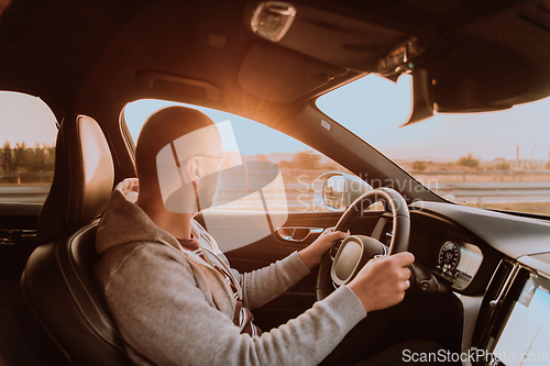 Image of A man with a sunglasses driving a car at sunset. The concept of car travel