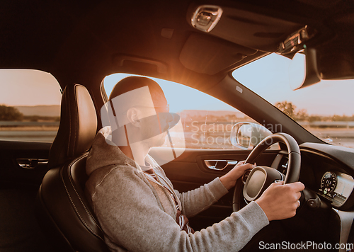 Image of A man with a sunglasses driving a car at sunset. The concept of car travel