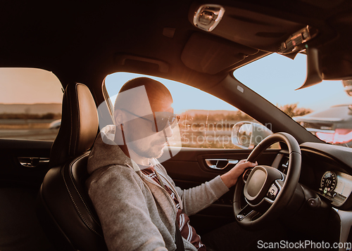 Image of A man with a sunglasses driving a car at sunset. The concept of car travel