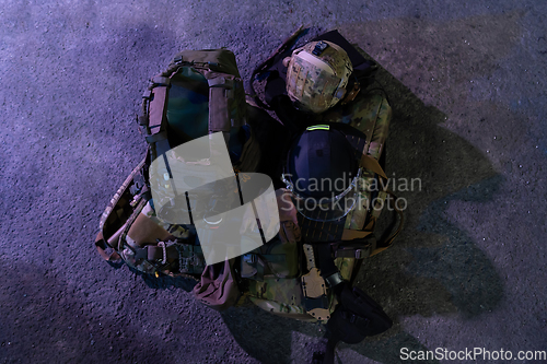 Image of Army body armor, helmet and ammunition, Kalashnikov assault rifle with matrons and first aid tourniquet composition on brown wood. Army body armor. flat laying. military concept.