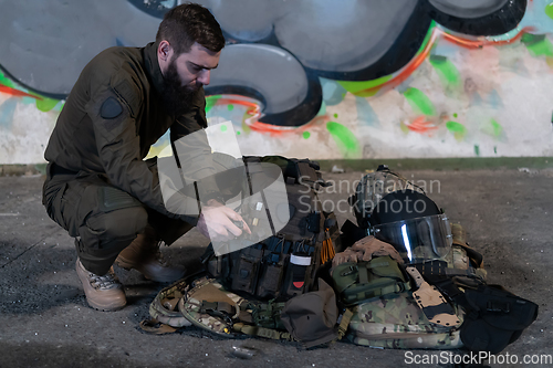 Image of Army body armor, helmet and ammunition, Kalashnikov assault rifle with matrons and first aid tourniquet composition on brown wood. Army body armor. flat laying. military concept.