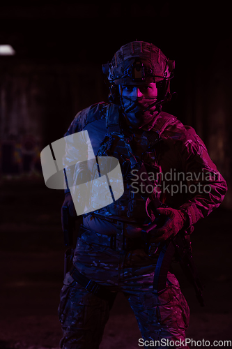 Image of Soldier of army elite forces, special security service fighter with hidden behind mask and glasses face, in helmet and load carriage system, aiming with service pistol low key.