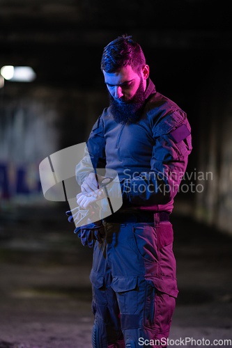 Image of Modern warfare soldier checking navigation, time and other information on a smartwatch. Dark night black background.