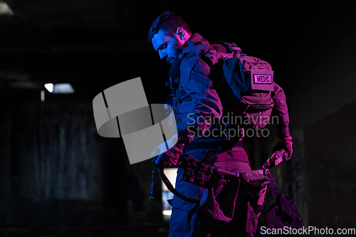 Image of Army soldier in Combat Uniforms with an assault rifle and combat helmet night mission dark background. Blue and purple gel light effect.