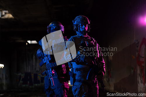Image of Modern warfare soldiers in dark with combat ammunition and weapons in the hands of equipped laser sights are in battle order. Mixed media.