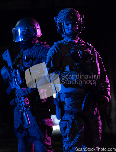 Image of Modern warfare soldiers in dark with combat ammunition and weapons in the hands of equipped laser sights are in battle order. Mixed media.