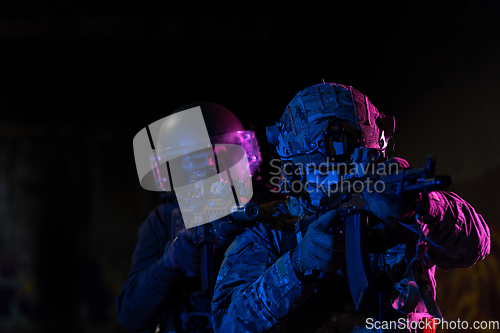 Image of Modern warfare soldiers in dark with combat ammunition and weapons in the hands of equipped laser sights are in battle order. Mixed media.