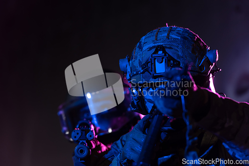 Image of Modern warfare soldiers in dark with combat ammunition and weapons in the hands of equipped laser sights are in battle order. Mixed media.