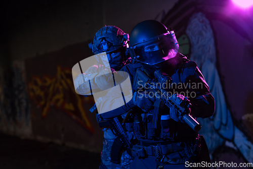 Image of Modern warfare soldiers in dark with combat ammunition and weapons in the hands of equipped laser sights are in battle order. Mixed media.