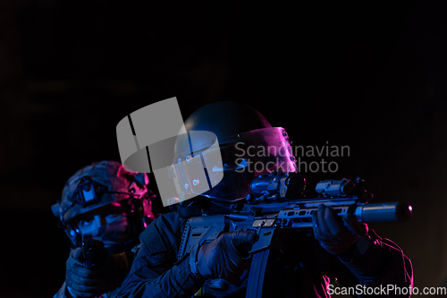 Image of Modern warfare soldiers in dark with combat ammunition and weapons in the hands of equipped laser sights are in battle order. Mixed media.