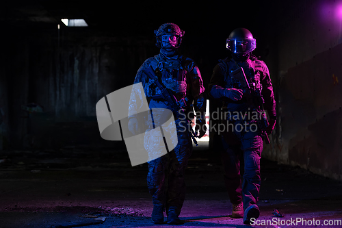 Image of Modern warfare soldiers in dark with combat ammunition and weapons in the hands of equipped laser sights are in battle order. Mixed media.