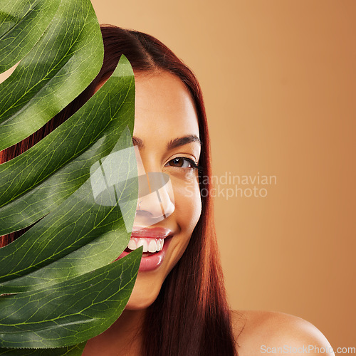 Image of Leaf, beauty and portrait of a happy woman in studio for natural dermatology, cosmetics or wellness. Skin care, nature and monstera plant for eco friendly facial of model person on brown background