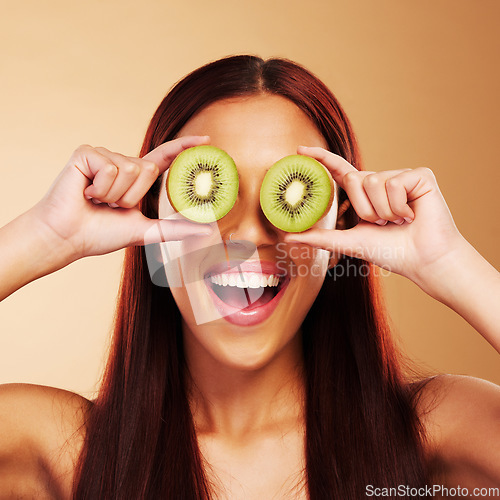 Image of Beauty, kiwi and a woman with skin care in studio for natural dermatology, cosmetics or glow. Facial, fruit and healthy diet for vitamin c and nutrition of excited model person on a brown background