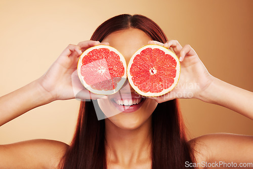 Image of Beauty, grapefruit and a woman with skin care in studio for natural dermatology, cosmetics or wellness. Facial, fruit and healthy diet for detox or nutrition of model person on a brown background
