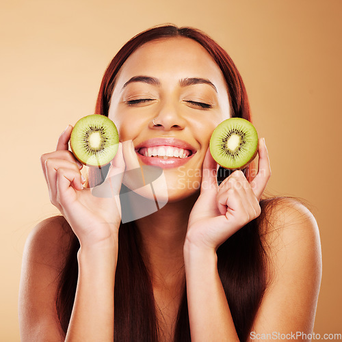 Image of Kiwi, beauty and face a woman with skin care in studio for natural dermatology, cosmetics or glow. Facial, fruit and healthy diet for vitamin c and nutrition of model person on a brown background