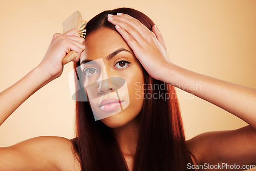 Image of Hair care, brush and portrait of a woman in studio for salon, hairdresser and wellness results. Hairbrush, beauty and shampoo for growth and shine of an aesthetic model person on a brown background