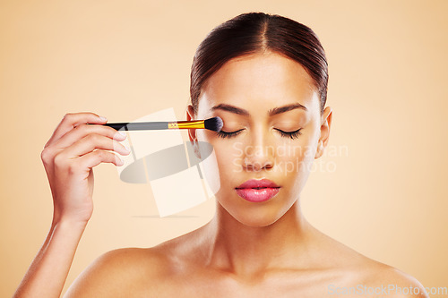 Image of Makeup, brush and woman with cosmetic beauty product application for skincare isolated in a studio brown background. Eyelid, elegant and powder for cosmetology aesthetic, glow and soft skin glamour