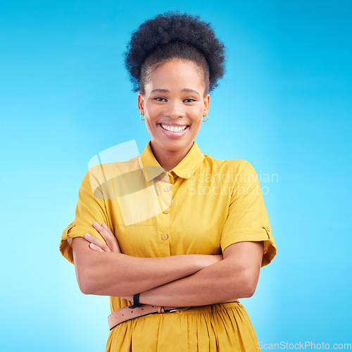 Image of Black woman, portrait and happy in studio with a smile, confidence and a positive mindset. Fashion, arms crossed and African female model person in casual clothes on a blue background for motivation