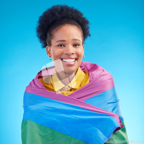 Image of African woman, pride flag and studio portrait for smile, support or inclusion for lgbtq by blue background. Lesbian girl, rainbow fabric or happy in solidarity, protest or gay freedom for equality