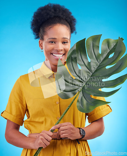 Image of Fashion, portrait and black woman with plant on blue background for eco friendly, organic and natural clothes. Nature, happy and female person with monstera leaf for sustainable clothing in studio