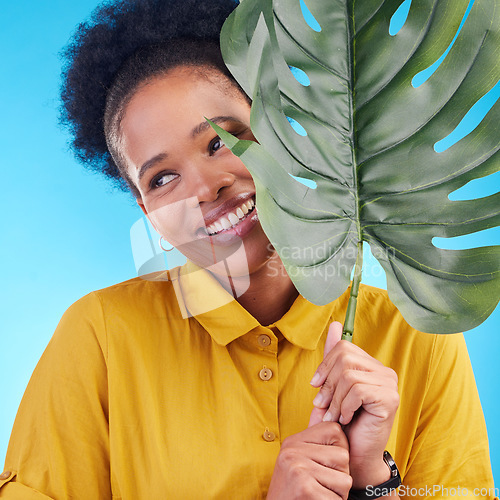 Image of Fashion, happy and black woman with plant on blue background for cosmetics, makeup and beauty. Nature, studio and female person with monstera leaf for organic, natural and detox products for wellness