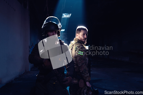 Image of Modern warfare soldiers in dark with combat ammunition and weapons in the hands of equipped laser sights are in battle order. Mixed media.