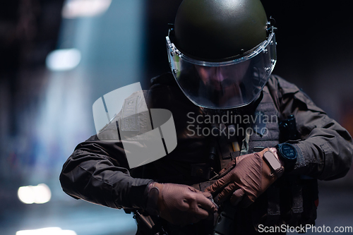 Image of Army soldier in Combat Uniforms with an assault rifle and combat helmet night mission dark background. Blue and purple gel light effect.