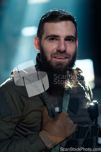 Image of Army soldier in Combat Uniforms with an assault rifle and combat helmet night mission dark background. Blue and purple gel light effect.