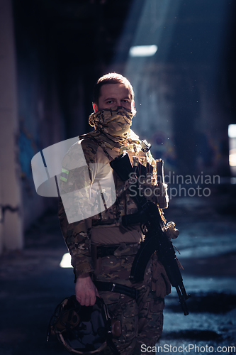 Image of Army soldier in Combat Uniforms with an assault rifle and combat helmet night mission dark background. Blue and purple gel light effect.