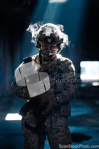 Image of Army soldier in Combat Uniforms with an assault rifle and combat helmet night mission dark background. Blue and purple gel light effect.