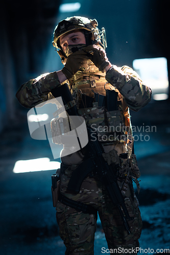 Image of Army soldier in Combat Uniforms with an assault rifle and combat helmet night mission dark background. Blue and purple gel light effect.