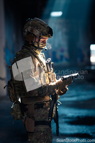 Image of Soldier of army elite forces, special security service fighter with hidden behind mask and glasses face, in helmet and load carriage system, aiming with service pistol low key.