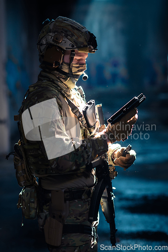 Image of Soldier of army elite forces, special security service fighter with hidden behind mask and glasses face, in helmet and load carriage system, aiming with service pistol low key.