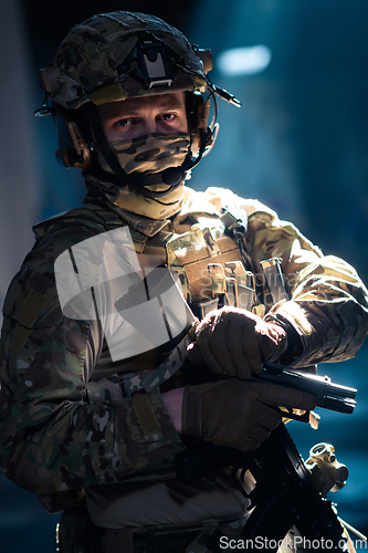 Image of Soldier of army elite forces, special security service fighter with hidden behind mask and glasses face, in helmet and load carriage system, aiming with service pistol low key.