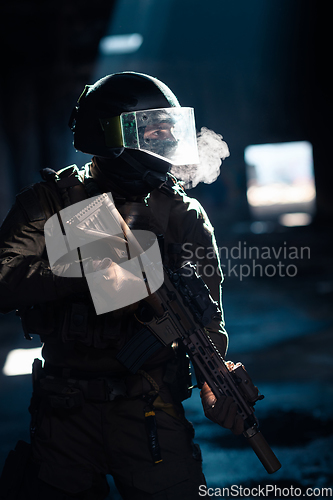 Image of Army soldier in Combat Uniforms with an assault rifle and combat helmet night mission dark background. Blue and purple gel light effect.