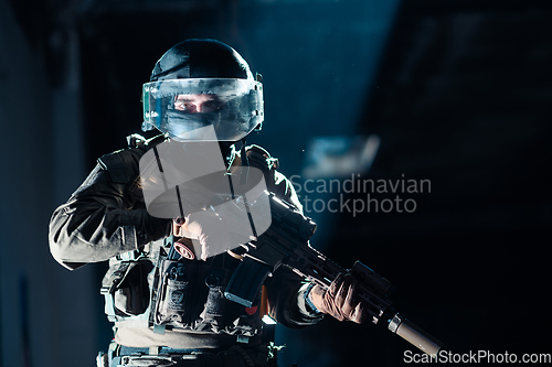 Image of Army soldier in Combat Uniforms with an assault rifle and combat helmet night mission dark background. Blue and purple gel light effect.