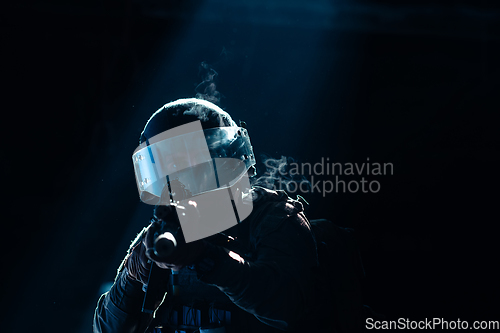 Image of Army soldier in Combat Uniforms with an assault rifle and combat helmet night mission dark background. Blue and purple gel light effect.