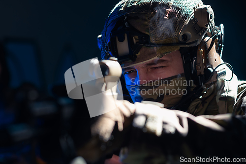 Image of Army soldier in Combat Uniforms with an assault rifle and combat helmet night mission dark background. Blue and purple gel light effect.