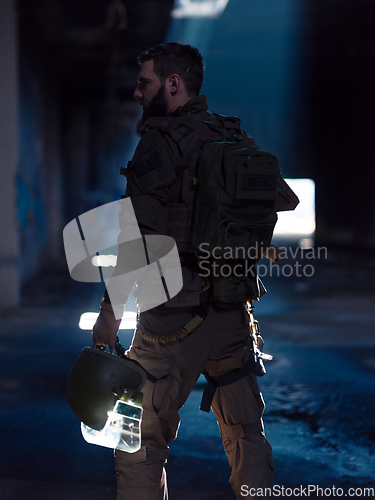 Image of Army soldier in Combat Uniforms with an assault rifle and combat helmet night mission dark background. Blue and purple gel light effect.