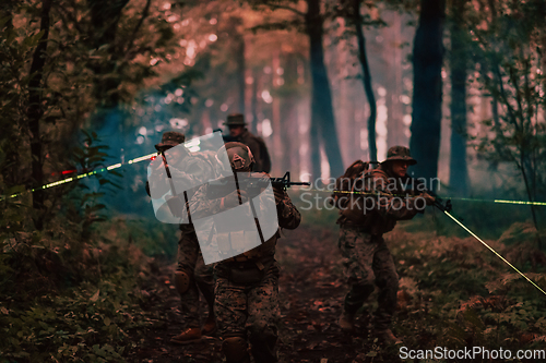 Image of Soldiers squad in action on night mission using laser sight beam lights military team concept