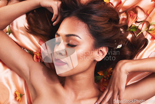 Image of Top view, cosmetics and woman in bed with flowers for glow or dermatology with luxury facial. Cosmetology, beauty and face with girl wearing makeup for natural grooming or self care for spa treatment