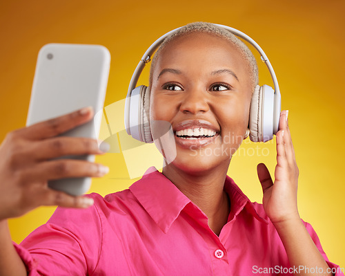 Image of Selfie, smile and black woman with music headphones in studio, streaming or subscription on yellow background. Podcast, profile picture and lady social media influencer online for radio or blog post